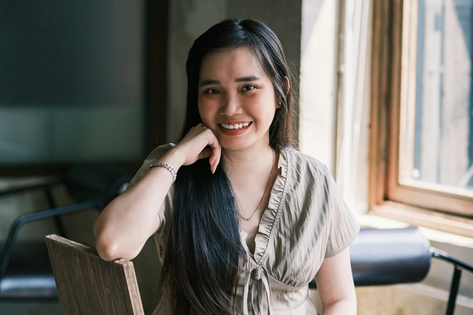 Mujer joven sonriendo junto a una ventana