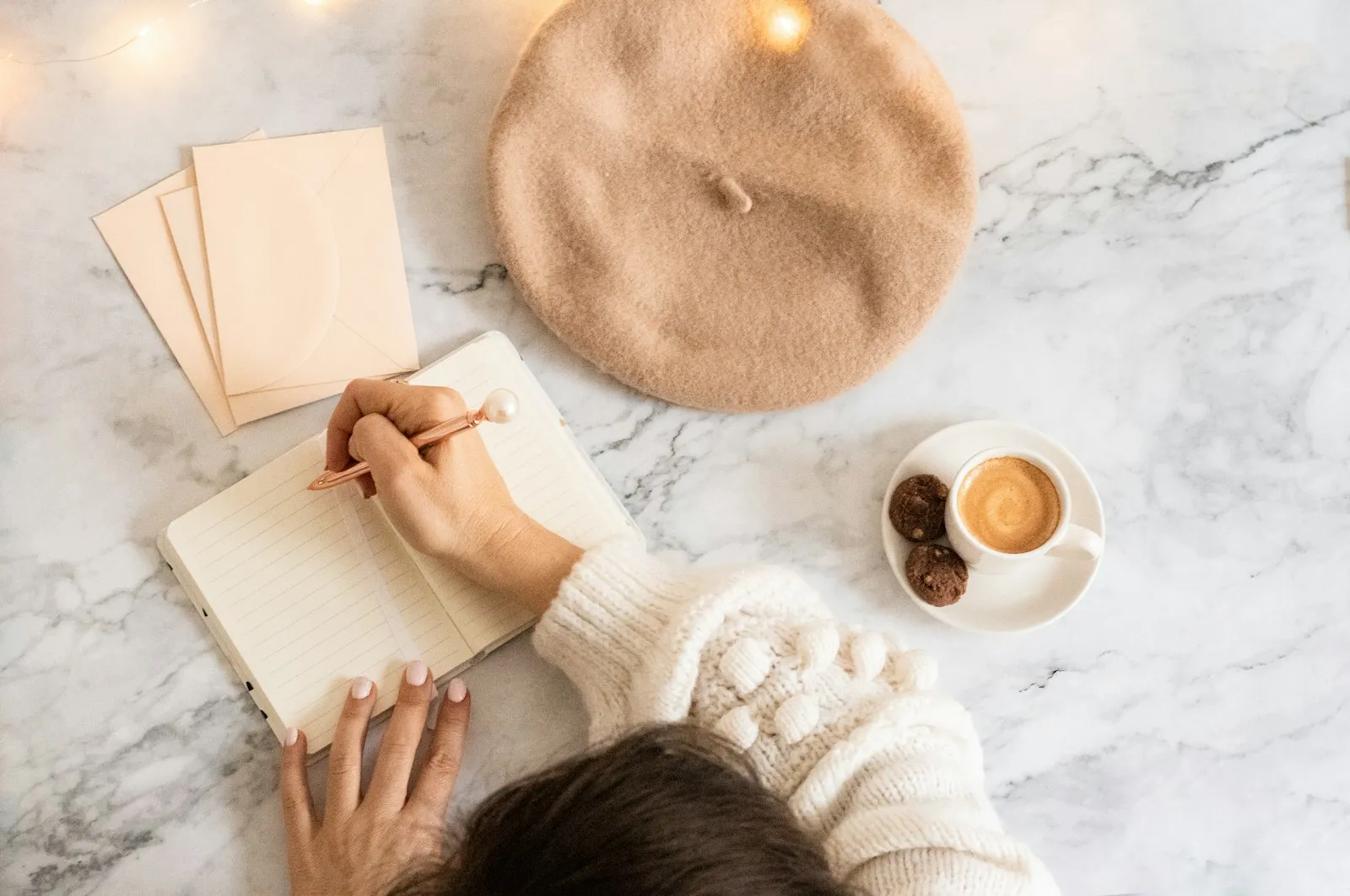 Persona escribiendo en su diario con una bebida caliente