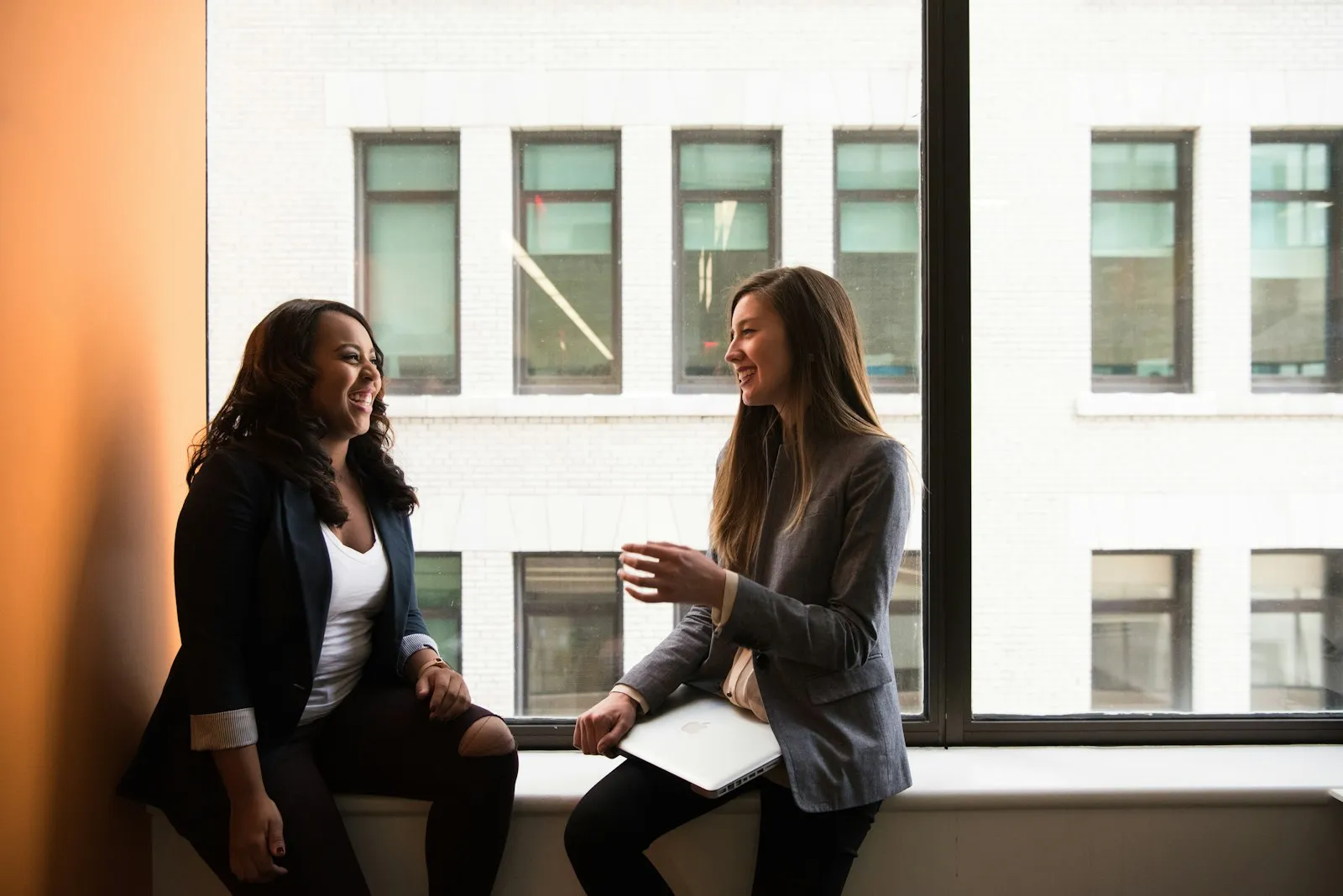 Dos mujeres platicando junto a una ventana