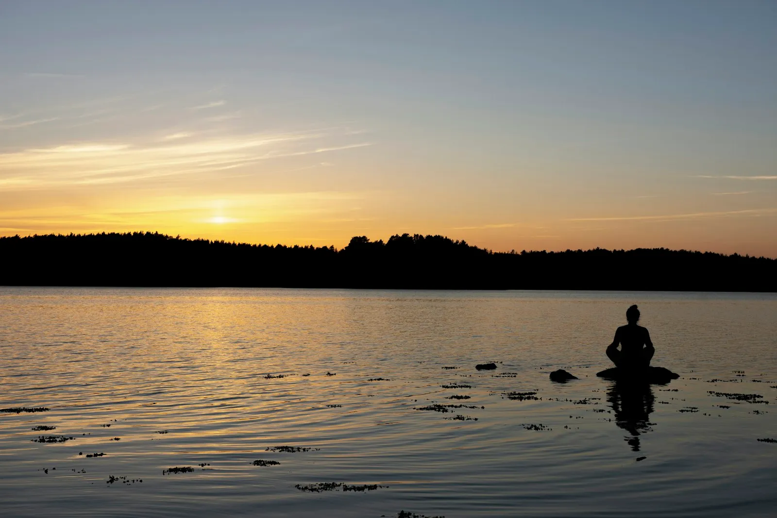 Persona meditando frente a un lago