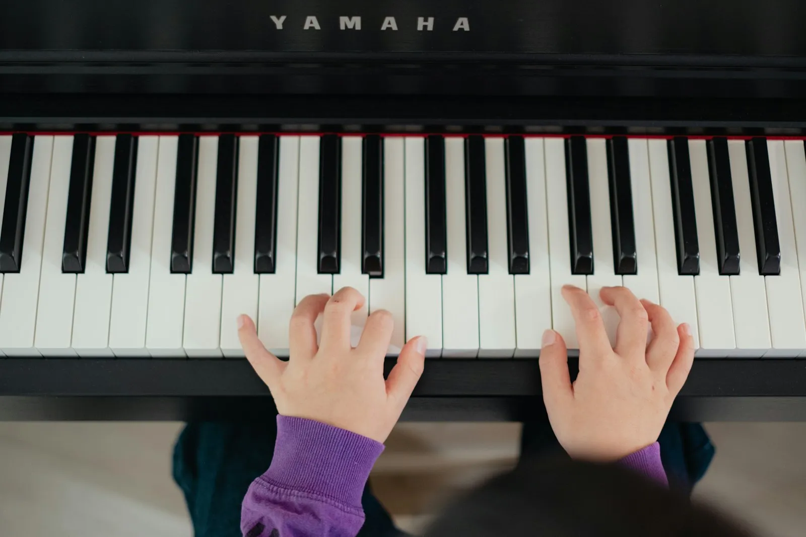 Manos de una niña aprendiendo a tocar el piano