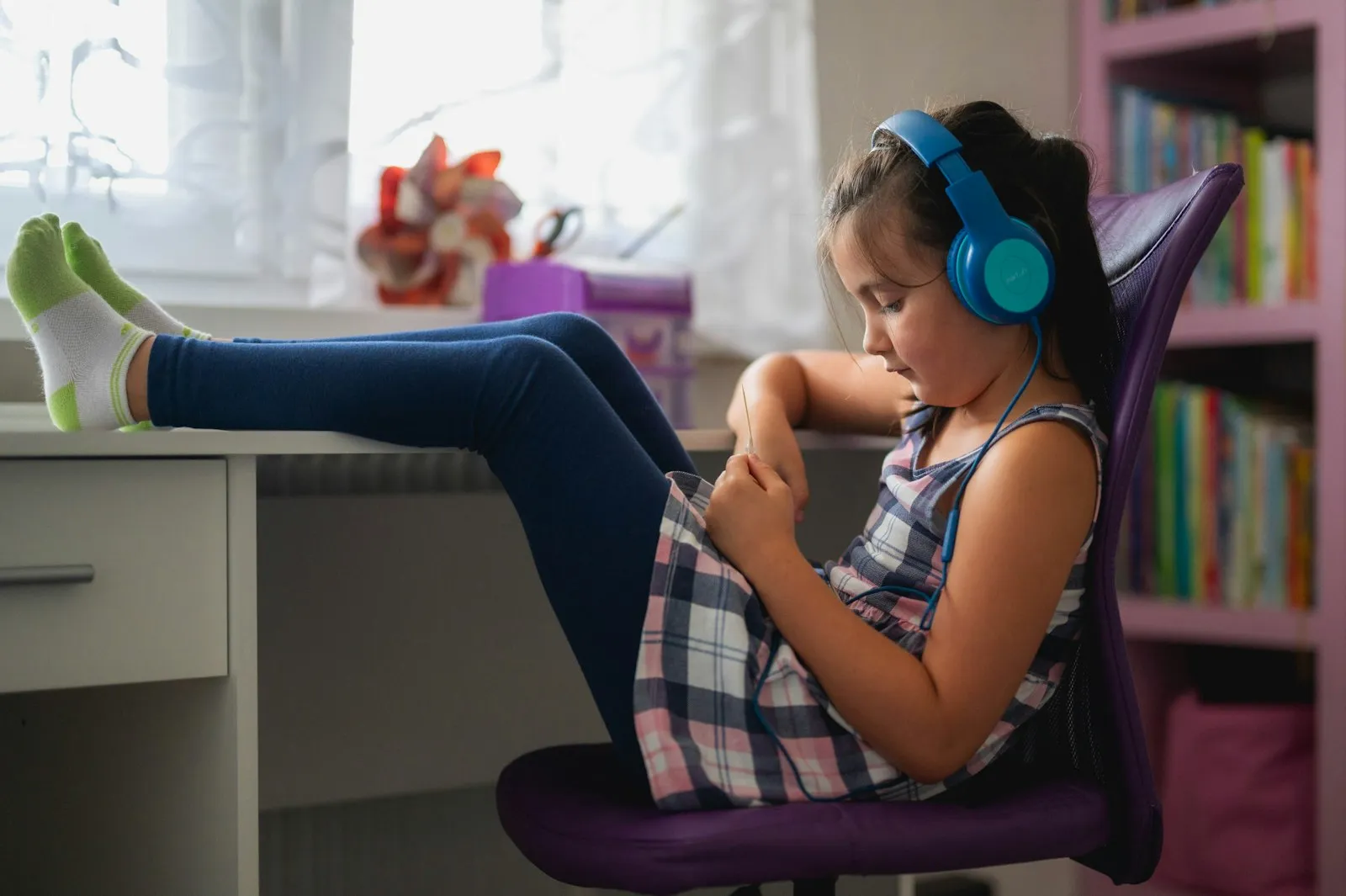 Niña leyendo en su escritorio con audífonos