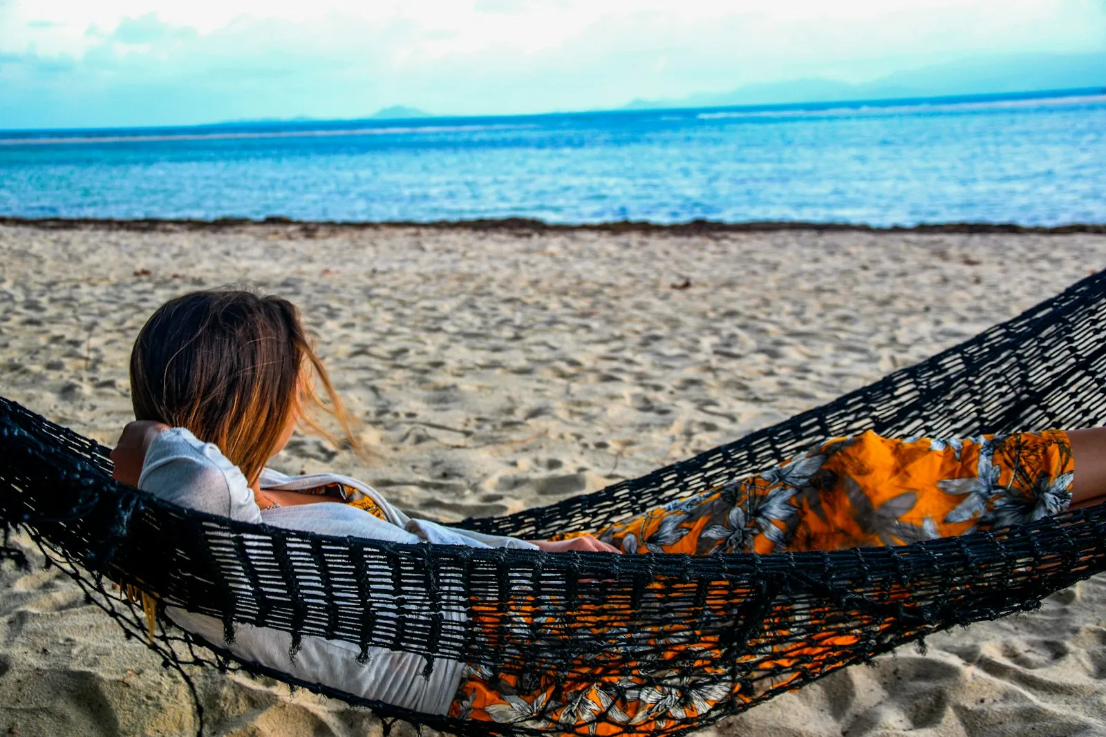 Mujer descansando en una hamaca en la playa