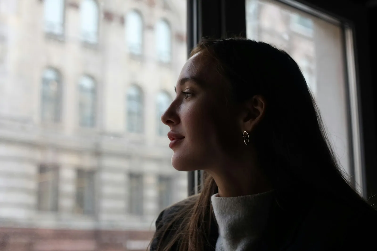 Mujer mirando por la ventana hacia la ciudad